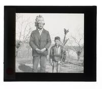 Lantern Slide #210:  Native American man wearing head dress, child holding spear