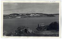 3-10-h: Unidentified body of water with settlement in background