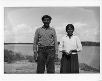 A211: Angus Owen (Aankus) and Red Bird Owen (Miskwa'o), standing near the river, Pauingassi, Manitoba, circa 1930s