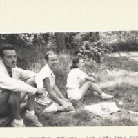 The Carlsons and Patsey Taylor, sitting outdoors on grass.