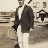 Loeb, standing outside, holding tennis racket.