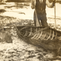 9-16-o: Man and dog beside completed canoe.