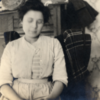 9-18-n: Woman, seated indoors, dresser in background.