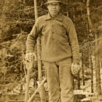 9-19-e: Man standing on logs with shovel, postcard.