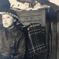 9-18-a: Young Penobscot girl, seated, dresser in background