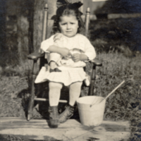 9-10-c: Ernestine Tomah, seated outside in wooden chair.