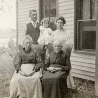 9-9-g: Four adults, one child, outside, house in background.