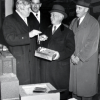 W. F. G. Swann, standing with other men, placing items in corner stone.