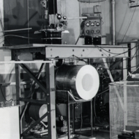 View of unidentifed man standing beside scientific equipment.