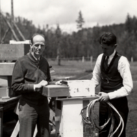 Full length view, two unidentified men, standing outside, working on equipment for stratospheric flight.