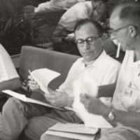 I. M. Lerner and Marcus Roades, seated, holding papers, Tokyo, 1956.