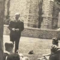 Richard Harrison Shryock standing outside near tree and seated people.