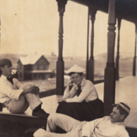 Unidentifed woman and two men, full length, seated on porch "after tennis."