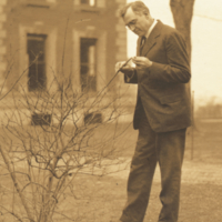 Joseph Russell Smith, standing outside examing plant.