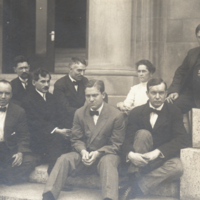 Unidentifed group of seven men and one woman, seated outside on steps at Rockefeller Institute.