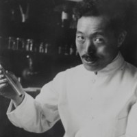 Hideyo Noguchi holding beaker in laboratory.