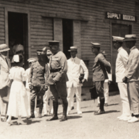 Gen. Wood tipping his hat to a nurse, surrounded by unidentified men and women.