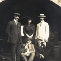 Heiser and four unidentified people outside under stone arch.