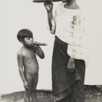 Unidentified Philippino woman and young girl, full length, 3/4 profile, informal, standing smoking cigars.