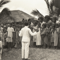 Gen. Wood, with hand on child's head as a man in white addresses a crowd.