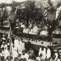 View of large gathering with unidentified man standing, addressing the crowd.