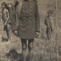 Full lenth portrait of man in uniform shirt and helmet, legs bare.