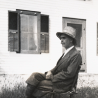 Landsteiner seated in chair outside with hat.