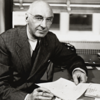 Heiser seated at desk holding paper, 1943