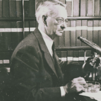 Edwin Grant Conklin, side view, in library with microscope.