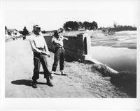 F-081: Couple standing in road near water 