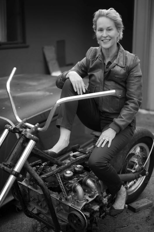 Black and white image of Frances Arnold posed on a motorcycle.