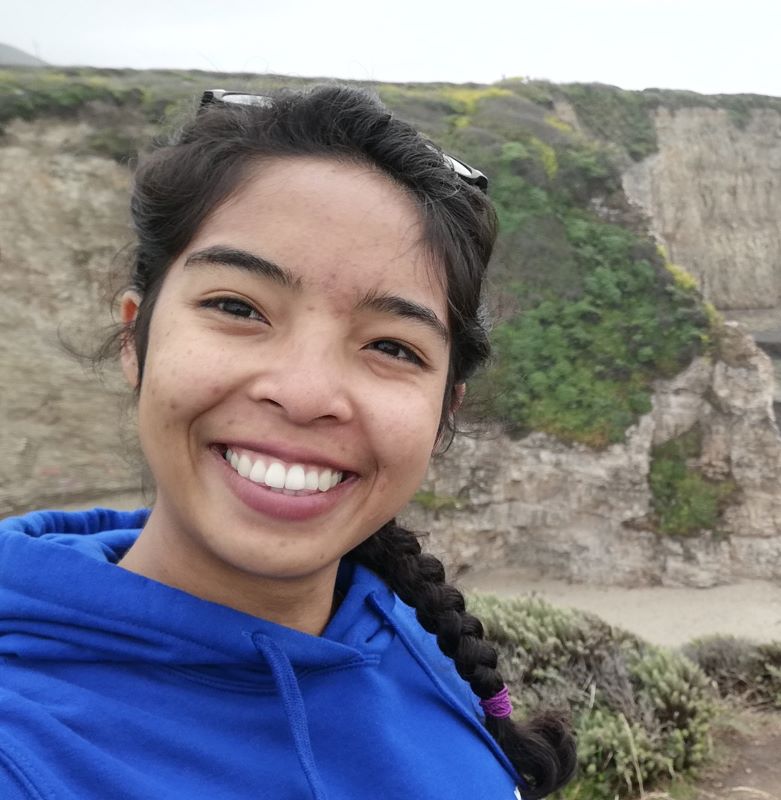 Selfie of Ramananjato in front of a rugged cliff with shrubbery in the background.