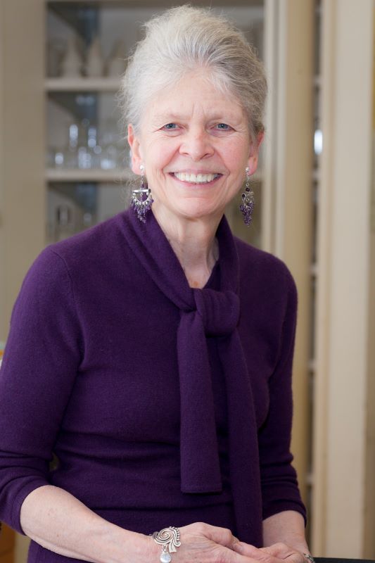 Formal portrait of Steitz wearing all purple: purple sweater, purple scarf, amethyst earrings.